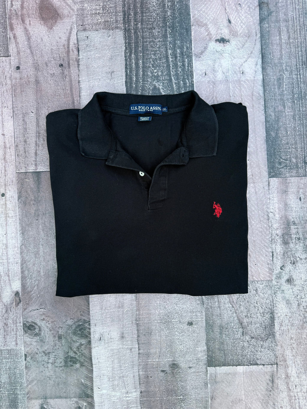 A folded black polo shirt with a small red embroidered U.S.