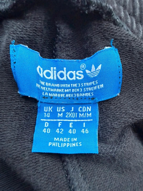 Close-up of a blue Adidas interior size label sewn onto black plush fabric.
