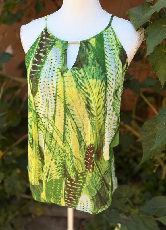 Inc International Blouse A sleeveless halter-style top with a green and yellow botanical leaf print, displayed on a white mannequin torso outdoors with green leaves and a brick wall in the background.
